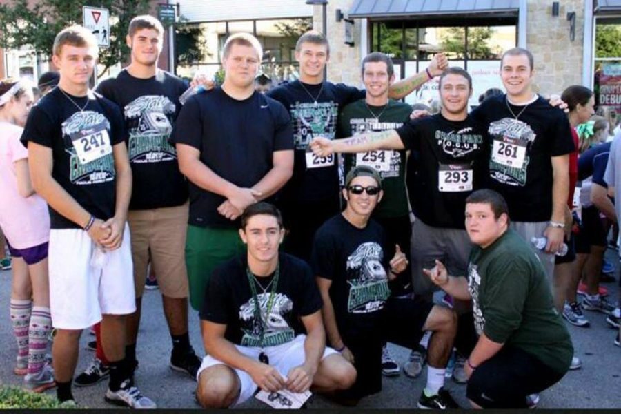 Members of the varsity football team cheer on honorary Timberwolf, Joshua Edmondson during the Champions4Children marathon on Sept. 23. Photo courtesy of The Support Joshua facebook page.