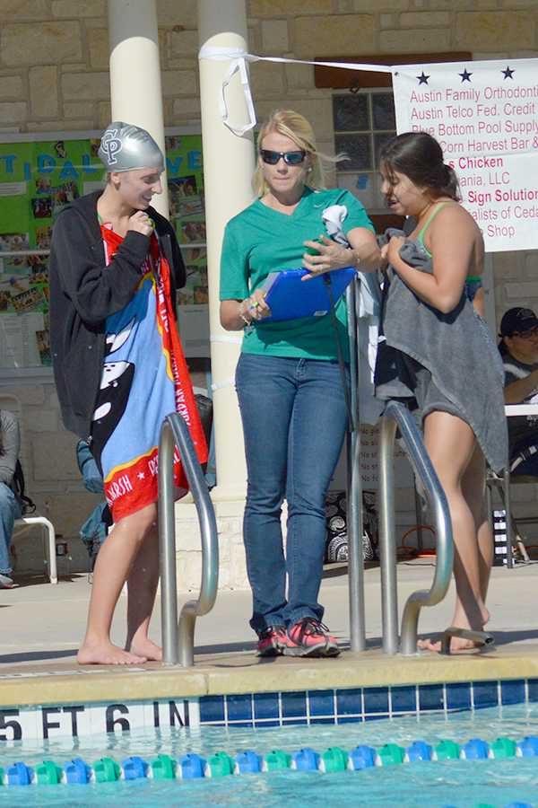 Senior Caroline Kessler, Coach Meghan DeWees and Mason Luna-Howell talk strategy during a tri-meet against Leander and Stony Point on Oct. 4. The team won the meet with a total point score of 302. The best part of the meet was being able to cheer everyone else on, sophomore Marian Bouchot said.