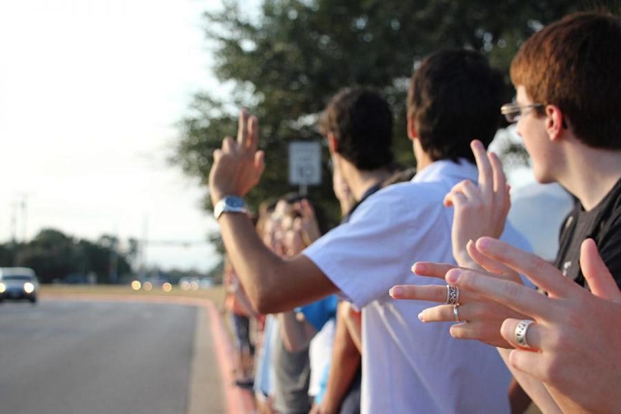 PALS students wave at cars coming into school on Oct. 8 in memory of past faculty member Dana Pharr. It was a wonderful experience to be able to give the student body and faculty one last memory of Dana, senior Karly Quinn said. I think everyone appreciated it and took something away from it.
