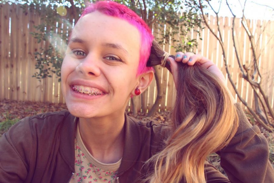 Sophomore Deana Trautz holds up her cut brown hair to her freshly dyed pink buzz cut.  I dont want them [society] to be intimidated by a color or something that is not normal, Trautz said. 