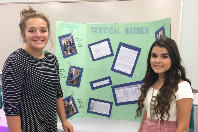 Seniors Megan Hamma and Lindsey Buggi pose next to their project for EcoAudit. 