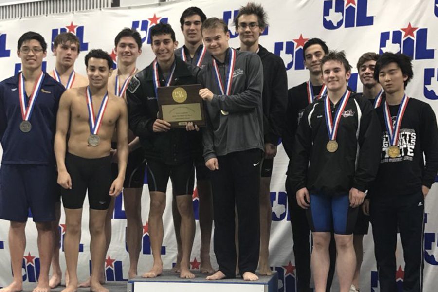 Vladimir Ivanov and the boys 200 yard freestyle relay team stand atop the first place podium and hold their state trophy.