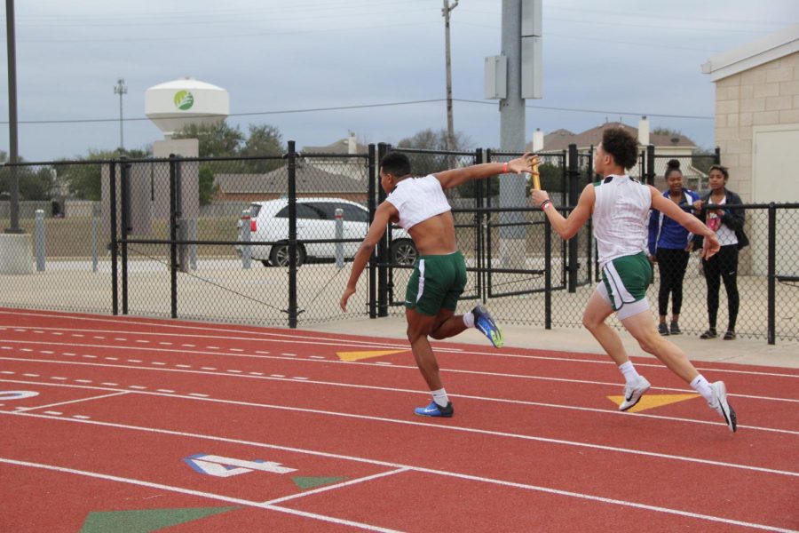 Junior+Eric+Shine+hands+the+baton+off+to+senior+Aries+Ramos+in+the+4X100++meter+relay+race+on+Feb.+16.