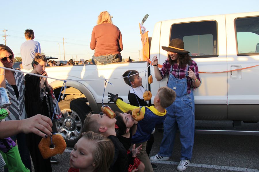 Holding up the string, senior Cameron Niemietz represents the STAND club at Trunk or Treat on Oct. 26. Niemietz said that the sweet treats made for a successful game. I really enjoyed getting to see how the kids lit up because they only had to eat a donut and instantly got their treat, Niemietz said. Trunk or Treat allows the community to come together and just have a little party where we all get to dress up and play games.