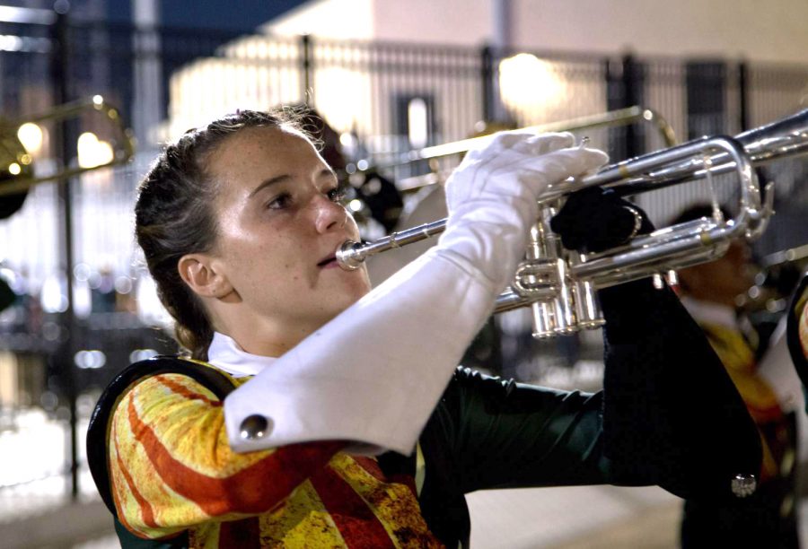 Playing trumpet,  junior Kaity Rhine plays with the rest of the band at an away football game against Conally. I love playing my trumpet, Rhine said.