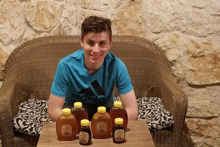 Bee+keeper%2C+senior+Rich+Daugherty%2C+sits+with+honey+that+he+and+his+father+packaged+using+hives+from+their+backyard.+Daugherty+sells+honey+and+said+there+is+more+to+their+business+than+honey..+%E2%80%9CWe+have+different+aspects+to+the+business%2C%E2%80%9D+Daugherty+said.+%E2%80%9CWe+have+our+honey+production%2C+our+hive+removals+and+then+we+also+have+out+candle+production+that+we+are+starting.%E2%80%9D