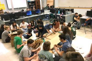 By cutting and gluing cardboard, and painting them green, students help make battery trash cans on April 3, 2018 in EIT.