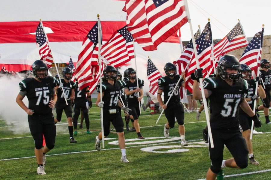 Showing their American Pride, CPFB enters the field before their match up against Hutto on Oct. 20. The Wolves beat the hippos 20-16 in a close game. The atmosphere was awesome, Hernandez said. Our student section was out there loud and proud and they definitely had an effect on the game.