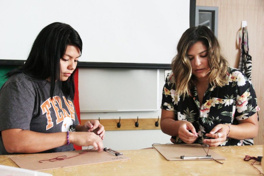 Senior Faith Elliott and junior Izzy Castillo make bracelets for Rwanda during den on Sep. 17. After her trip to Rwanda last year, Elliott decided this year to bring with her handmade friendship bracelets. They are such an uplifting, happy community [in Rwanda], Elliott said. They love knowing that other people from across the world, like the kids, are thinking of them and making bracelets, thinking of them and for them. They love anything that came from the U.S. 