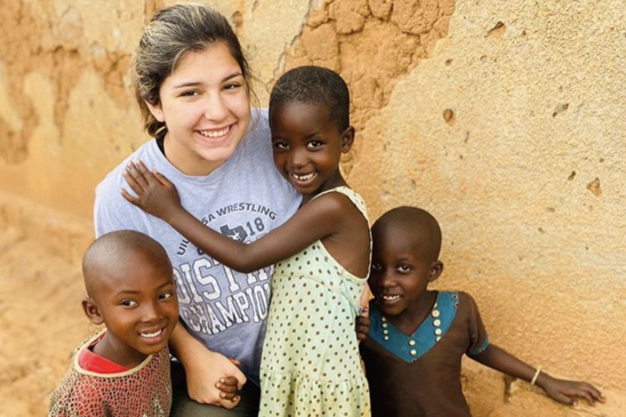 Posing+with+two+children+on+a+mission+trip+to+Rwanda%2C+senior+Faith+Elliott+grows+her+love+of+service+and+exploration.+Elliott+says+what+she+values+the+most+in+her+trips+is+the+opportunity+to+spend+time+with+children.+%E2%80%9CI%E2%80%99ve+never+been+particularly+fond+of+kids+but+my+heart+bursts+with+love+for+those+precious+kids+in+Rwanda%2C%E2%80%9D+Elliott+said.+%E2%80%9CThey%E2%80%99ve+been+through+so+much+and+they%E2%80%99re+still+all+filled+with+joy.%E2%80%9D