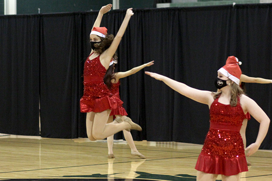 In a sparkly red ensemble and a Santa hat, freshman emerald Saxon Schroeder jumps on her count at the Celebrities winter show on Dec. 13. With the pandemic, Emeralds and other dancers have a limited number of performances this year. “We have had less performance opportunities which has been sad,” Schroeder said. “Otherwise, I love being an Emerald. Some of my close friends are in dance so it’s a lot of fun.”