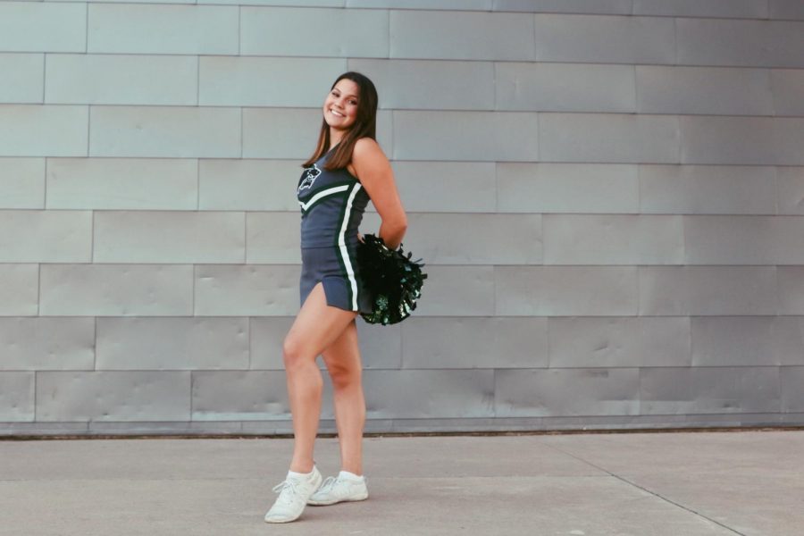 In her cheer uniform, senior Kaitlyn Armstrong poses for her senior pictures. According to Armstrong, to be a true cheerleader one must have the passion and willingness to adjust.  “To me, it’s essential to be dedicated, self-motivated and flexible to be a cheerleader,” Armstrong said. “Of course, skills are important, however, since our schedule sometimes is based around other sports, our schedules can change easily, thus flexibility. 