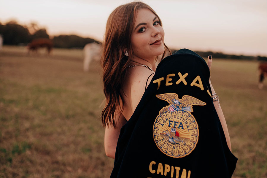Posing for senior pictures, senior Callie Hobbs shows her dedication to FFA with her District Officer jacket. Hobbs started FFA in the fall of 2016 when she was in seventh grade, and as a Junior FFA member, she raised show swine and went to shows around the county as well and around Texas. “I wanted to take pictures with my cattle to show off the livestock projects that I have spent months training, preparing, and showing,” Hobbs said. “These pictures serve as a way to look back on past memories and to give me a chance to see what my animals look like when the judge sees them from a different angle. Sometimes it is hard to know what to change or fix about my animal until I can see them from a different angle, but it’s hard to do that when I’m walking them so the pictures can help to show me what to improve.”