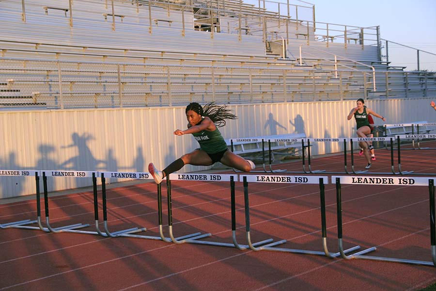 Junior+Amani+Graham+takes+to+the+skies+in+the+hundred+meter+hurdles.+This+was+the+varsity+girls+first+meet+of+the+season+and+they+faced+off+against+Leander+and+Rouse.+I+was+really+focused+on+not+screwing+up%2C+Graham+said.+I+made+sure+to+pull+my+trail+leg+down+to+make+my+next+steps+to+the+next+hurdle.+form+is+very+important+for+all+running+events%2C+but+especially+for+hurdles.
