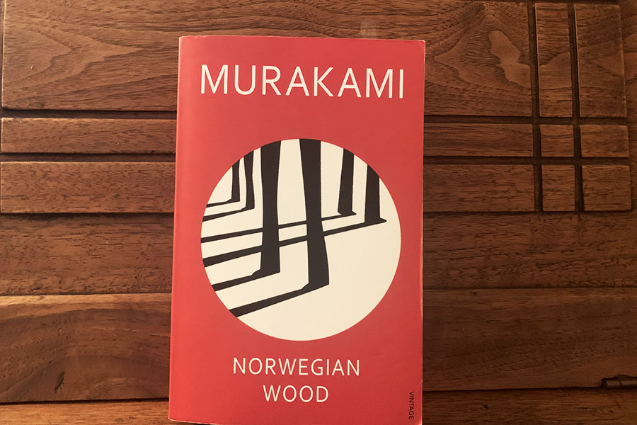 Japanese+writer+Haruki+Murakami+first+released+the+novel+that+propelled+him+to+international+recognition%2C+%E2%80%9CNorwegian+Wood%E2%80%9D+in+1987+and+has+released+28+books+in+total.+The+red%2C+white+and+black+cover+depicted+shows+what+appears+to+be+shadows+cast+under+slender+tree+trunks+correlating+to+the+title%2C+but+the+more+detailed+visual+shows+pairs+of+feet+with+two+people+facing+left+and+one+right.