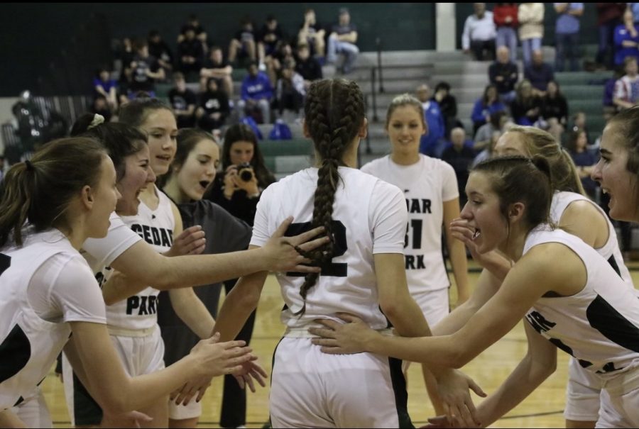 Cheering+for+their+teammate%2C+the+girls+varsity+basketball+team+rallies+around+senior+Megan+Woods+before+they+begin+a+game.+Throughout+Woods+high+school+career%2C+she+said+she+made+many+relationships+and+friendships+through+basketball%2C+volleyball+and+track.+%E2%80%9CI+have+built+a+lot+of+connections%2C+especially+at+this+school%2C%E2%80%9D+Woods+said.+%E2%80%9CI+have+met+some+lifelong+friends%2C+who+I+will+continue+to+adore+for+the+rest+of+my+life.