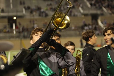 Lifting his trombone in the air, senior Collin Borenstein plays Metalshop at the Homecoming game against Cedar Ridge Sept. 8. Borenstein served as the brass section leader for the band this year. “It was a lot of fun,” Borenstein said. “We had a year of COVID-19 and there was no work and no socialization. Everyone got back in 2021 and people could have chosen not to buy in or to talk with each other, but everyone wanted to buy in and everyone was willing to put in a lot of work.”