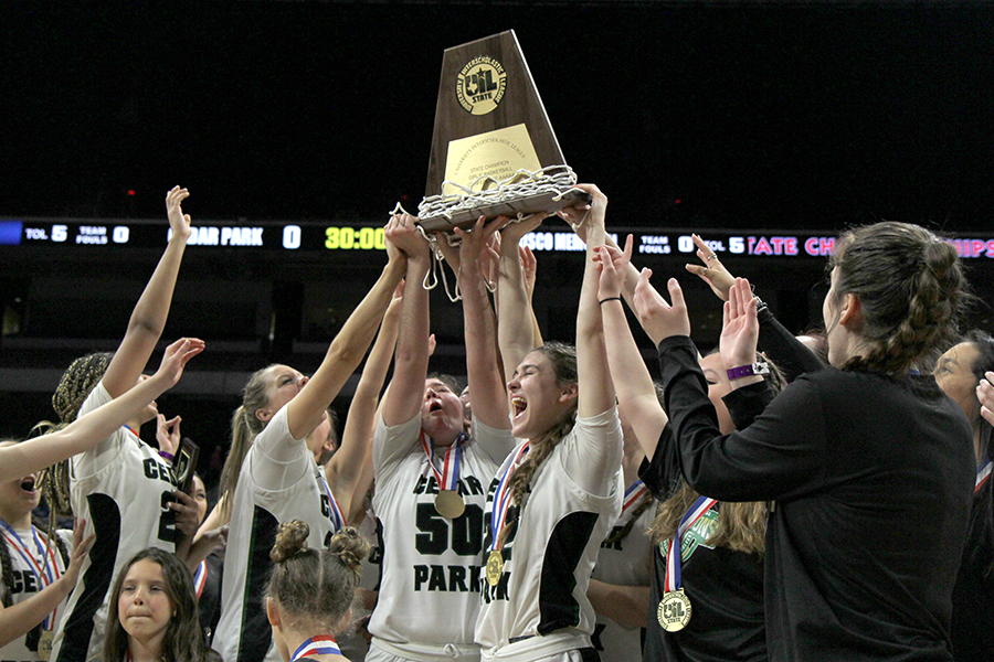 Senior Megan Woods holds up the State Championship trophy after helping the team win back to back 5A titles. 