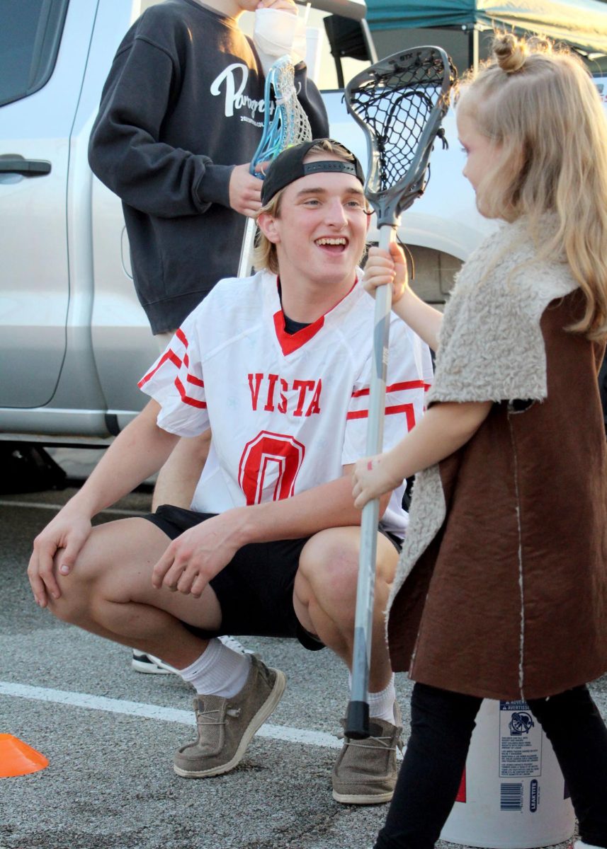 Smiling big, junior Hank Newman helps a little girl throw a lacrosse ball at the trunk or treat. During the trunk or treat, both the boys’ and girls’ lacrosse teams set up a lacrosse goal for kids to shoot at, and they handed out candy to the winners. “It was really fun helping the kids and getting to see their faces light up whenever they made a shot,” Newman said. “I also loved eating the candy.”