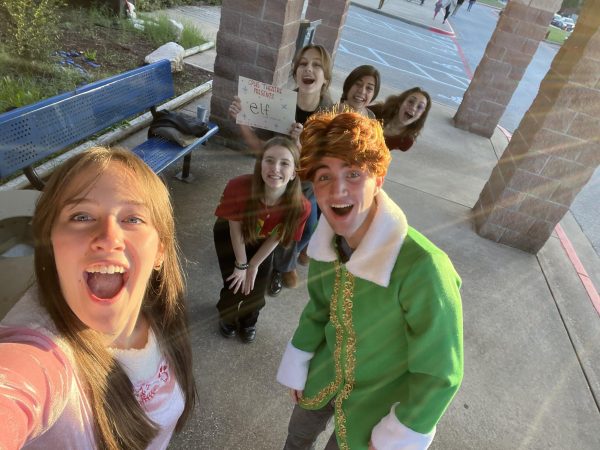 Taking a selfie with some of their castmates, including senior Aidan Cox, who plays Buddy the Elf, junior Brooke Ferguson shows off a sign presenting the arrival of “Elf. This year’s musical, “Elf” runs Dec. 1-3 in the CPHS PAC. “[Learning a new script is] always kind of a challenge,” Ferguson said. “You get a new cast and you get your own part. I’ve never worked closely with these people before. It’s a different environment and doing character work with someone new, trying to partner work and scene work is interesting. The script is good and it has a lot of jokes, it’ll be a lot of laughs.” Photo by Brooke Ferguson
