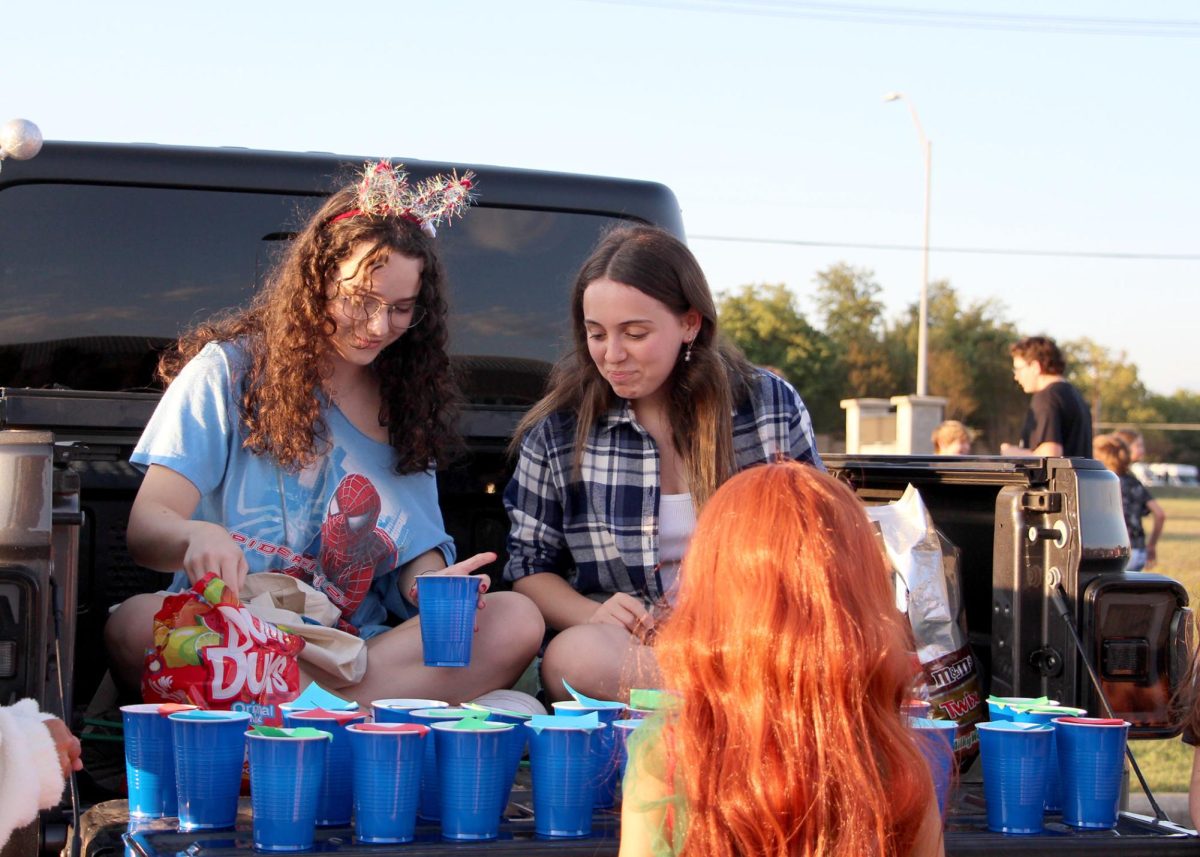 Making kids all around smile, Seniors Maya Persky and Omer Edery chat with a kid while setting up a game for Trunk or Treat. In their trunk, PALs created a roulette game for the kids to play. “We [had] them stand back and guess a number, and if they [guessed] it, then they [won] a lollipop,” said Persky. “We do a lot of Community Service in PALs, [and] we were there to entertain the kids and give them a good Trunk-or-Treat experience.”