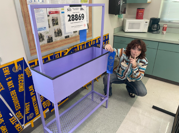 Senior Ash Foster poses next to her project she built for to attend the San Antonio Ag Mech show. Her purple planter built for her mom earned herself a blue ribbon. “I think it was really fun to learn how to paint,” Foster said. “We used spray paint primer and then two coats of paint and I thought that was really fun. We had to clean the entire thing. We had to wire wheel it and there was still splatter after and I spent like 3 hours cleaning. I had to put a hazmat suit on with a respirator. I absolutely loved it. I feel like Im in Monsters Inc right now. All the projects were all black and the only way you could see mine was because it was purple.”