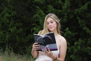 Holding her debut novel "Lorida," senior Lilly Stone poses with her self-published novel for her senior photos. Stone said that she is optimistic about what her future holds in the literary world, and is proud of how far she has come despite the odds. “It doesn't take a special skill set to write a book, and you don’t have to be anyone special to do it,” Stone said. “If you have the drive and motivation, you have to just keep pushing yourself to write even when you don’t feel like it, because, in the end, you will be proud of what you’ve accomplished.” Courtesy of Lilly Stone