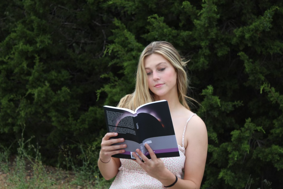 Holding her debut novel Lorida, senior Lilly Stone poses with her self-published novel for her senior photos. Stone said that she is optimistic about what her future holds in the literary world, and is proud of how far she has come despite the odds. “It doesnt take a special skill set to write a book, and you don’t have to be anyone special to do it,” Stone said. “If you have the drive and motivation, you have to just keep pushing yourself to write even when you don’t feel like it, because, in the end, you will be proud of what you’ve accomplished.” Courtesy of Lilly Stone
