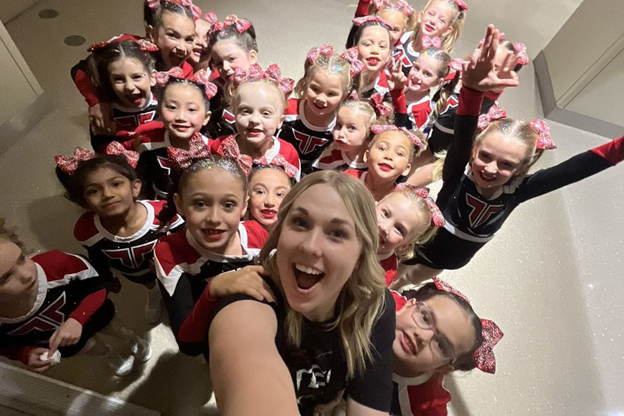 Smiling, senior Macy Alexander poses for a photo with the cheer team that she coaches. Alexander works as a junior coach at Tumble Tech, an all-star cheerleading gym. “I've always been someone that loves little kids and loves to work with children,” Alexander said. “I think my favorite part would probably be getting to see all the littles that I work with improve and get better day by day and see how dedicated they are to better themselves.”
