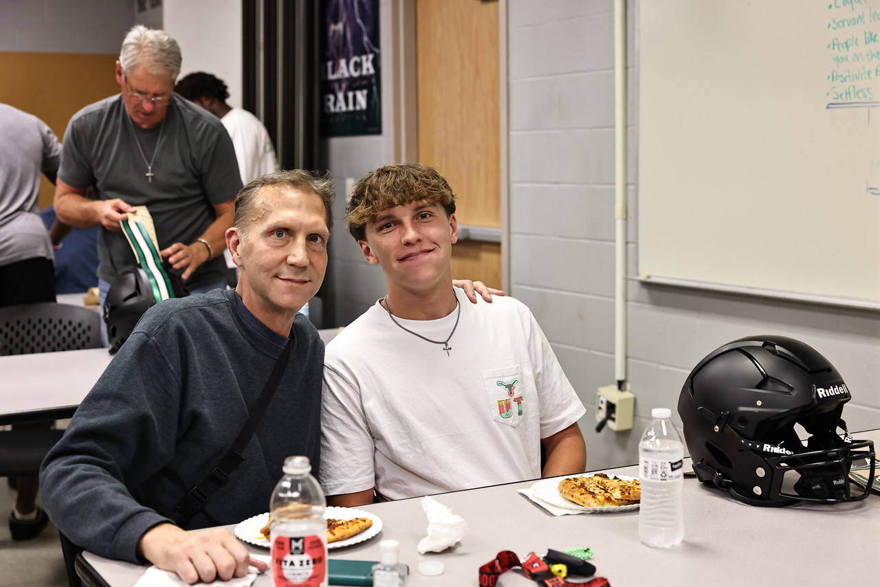 Smiling during the annual Decals with Dads, varsity starting quarterback and sophomore David Cooper and his dad Jim Cooper pose for a picture. During this varsity event, players and their dads get together to put new decals on their helmets. This year, in addition to being announced QB 1, David was also voted as one of six captains on the varsity team, a role that he had difficulty adjusting to as a younger player on varsity. “It was a struggle for me, being younger than everyone else and being a leader,” David said. “I wondered if [the team] would respect me, or if they would just see me as a younger person from a younger class. I think I've become a leader, [though] and let people know that even though I'm younger, I'm still going to lead them well.” Photo courtesy of Cedar Park Football SmugMug.