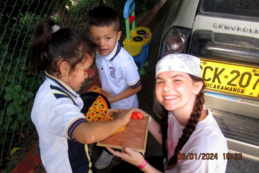 Holding a wooden pizza toy, senior Taylor Peterson plays with small children in Bucaramanga, Colombia. During the summer, Peterson traveled to Colombia to help build an elementary school that only had two classrooms but five or six grades with one teacher. “We add[ed] two more classrooms,” Peterson said. “It’s kind of hard when you have two or three grades in one classroom and you only have one teacher. It’s very hard to actually get some beneficial learning. [The extra classrooms will give the students] a better quality of education because they’ll actually have a place specific for their learning.” Photo by Taylor Peterson