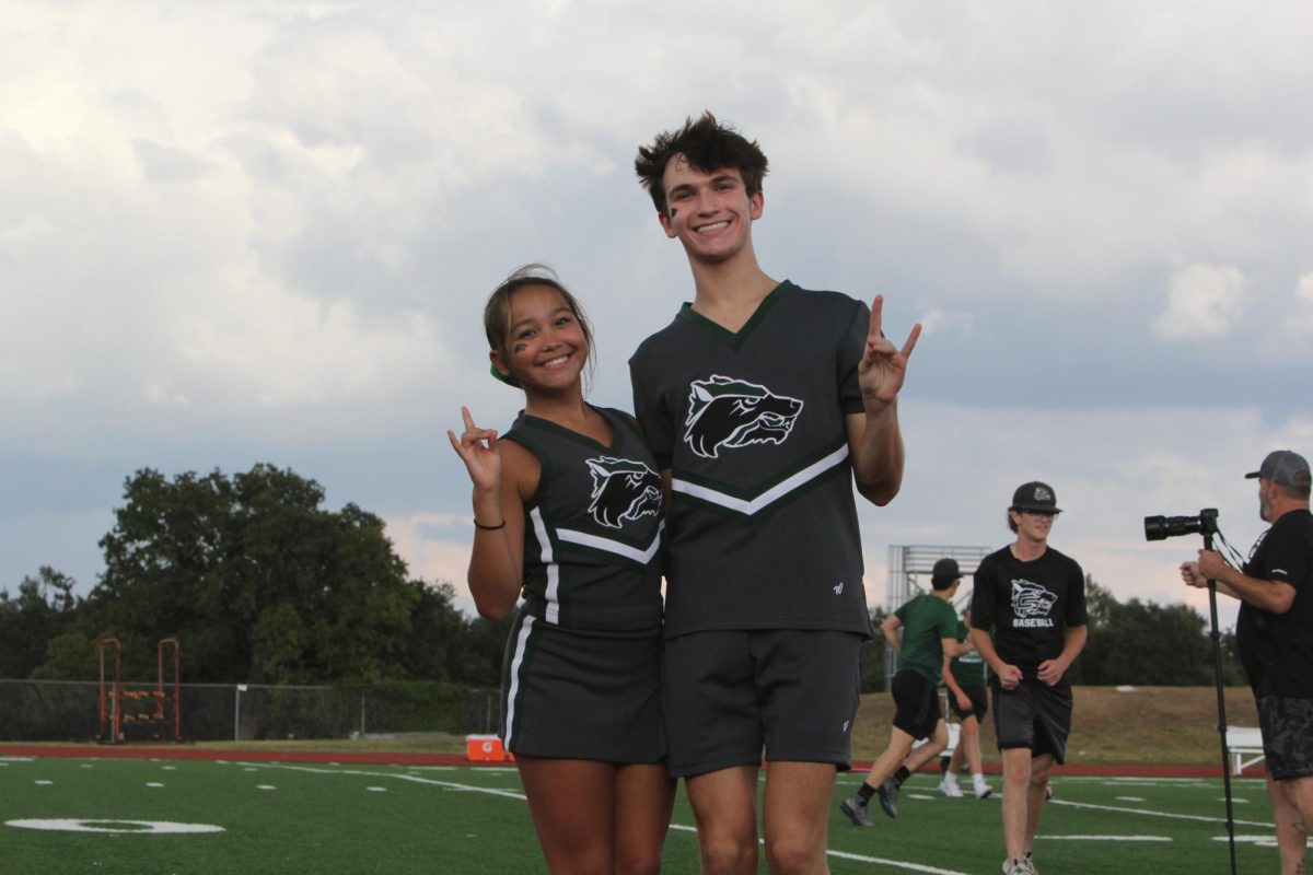 Standing in front of the field at a freshman football game, cheerleader freshman Jacob Gaudreau along with teammate freshman Bella Gibson pose for a photo during halftime of game. “[Cheer has] definitely given me a much more  outgoing personality,” Gaudreau said. “I used to be very introverted, so it's definitely made me more extroverted towards people.”