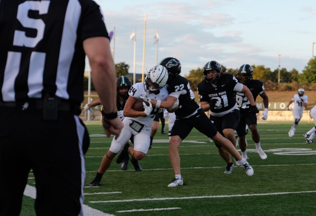 In the game on Sept. 9 against Vandegrift, sophomore varsity defensive back Hayden Hollander tackles a receiver, attempting to prevent a touchdown. The team practiced defensive drills during weekly practice to prepare for the match, which they won 49-46 in double overtime. “At practice, we start with backpedaling drills and then we go into tackling drills,” Hollander said. “After that, we have an interception drill. I like that I have control over the defense so I get to call the play." Photo by Alyssa Fox