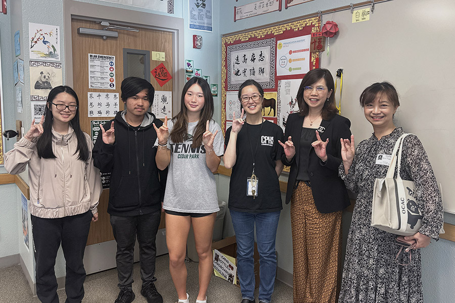 Holding up T-wolves, the tour group poses for a picture in the Chinese classroom. Sophomore Lydia Ou, junior Phu Trung and senior Yushan Pan gave a tour to Taiwanese diplomat Andrea Yang on Nov. 8. “I was so excited when I heard I would get to give the tour because it’s a big deal,” Ou said. “She’s from the US embassy for Taiwan, so she’s really important. I’m so privileged [to get this opportunity] and I’m so excited.” Photo by Skyler King