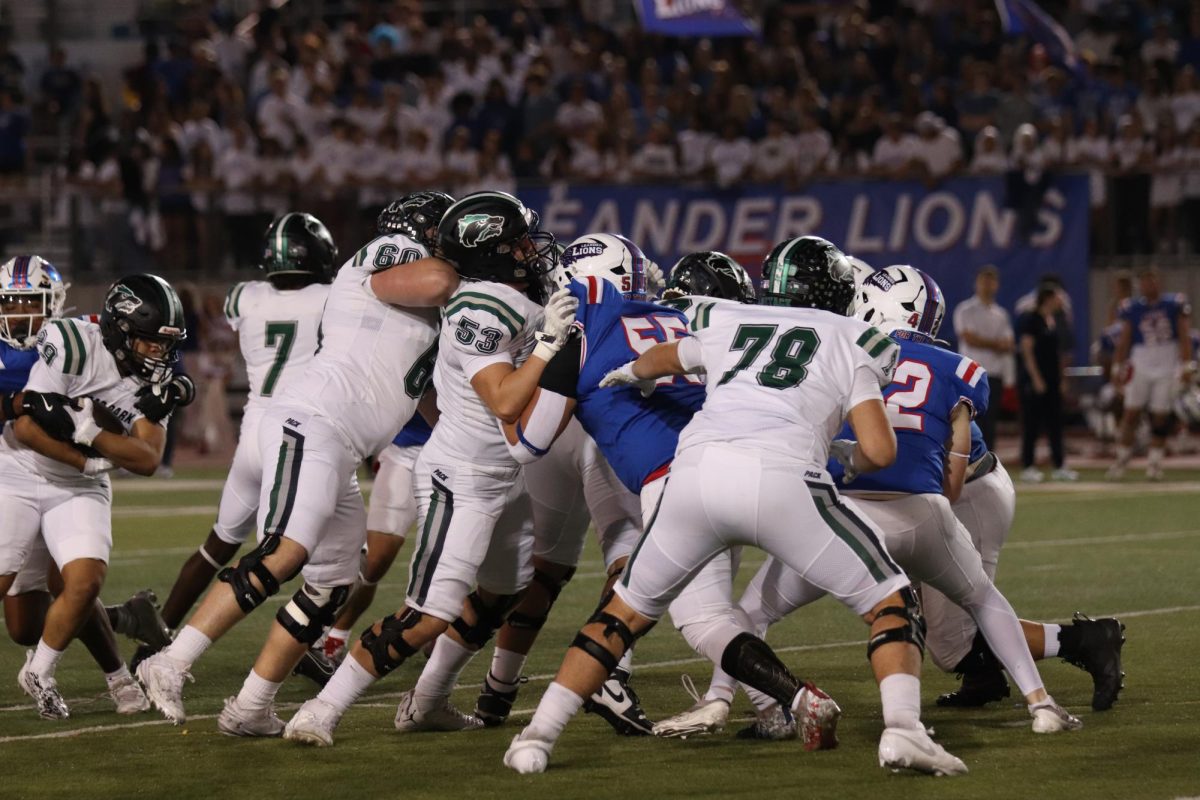 Blocking for his running back, sophomore varsity linebacker Brock Bungo works with his teammates to slow down the Leander Lions’ defense. On Nov. 1, the Timberwolves beat the Lions 47-21 at Bible Stadium. “I practice my position by making sure my hands and feet are all correct before the game and rehearse the plays in my head,” Bungo said. “It’s hard sometimes because not every play is perfect, so you have to make adjustments on the fly.” Photo by Julia Seiden