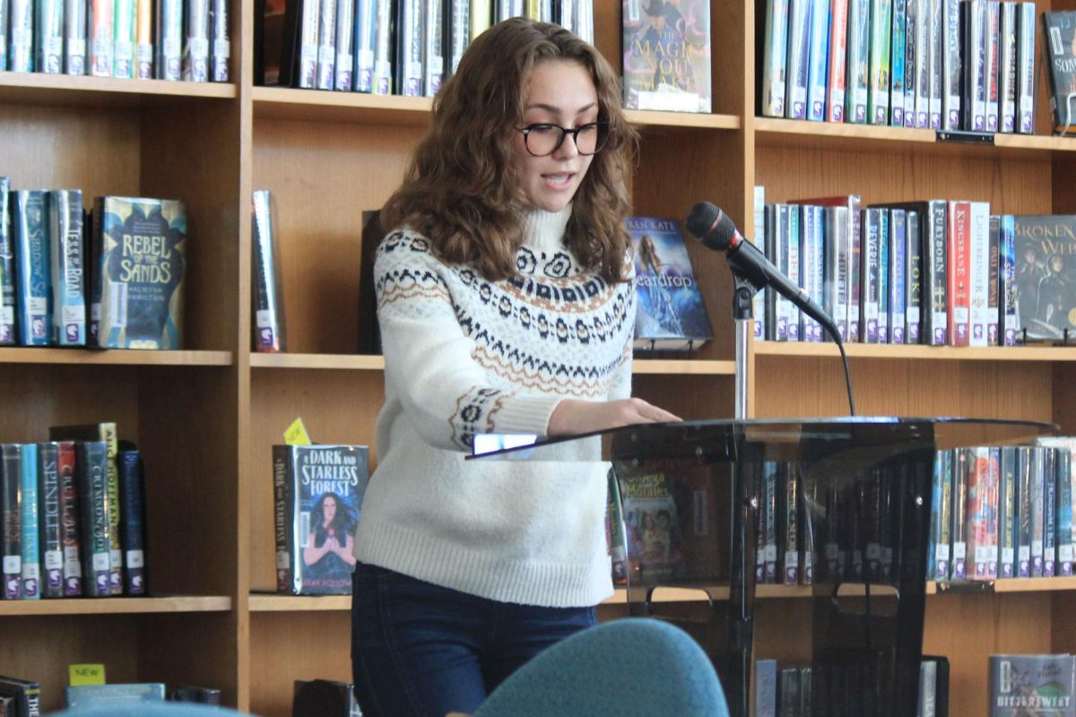 Standing in front of a small audience, senior Kimberley Walters shares a social criticism poem titled “Pity the Nation” by Lawrence Felinghetti. Every month, sponsored by the poetry club, the library hosts a poetry reading. “I never thought I would be interested in [poetry readings] because I’m not the biggest poetry fan,” Walters said. “I think poetry is a very succinct way to express feelings and get a story across. Whereas lots of books have a span of a whole story, but it’s put in a lot of words. The power of poetry is that you can be so succinct within, and there’s a lot of power within the words that are used.”