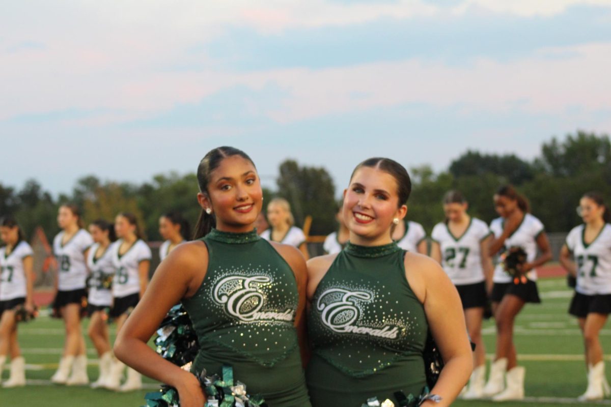 Smiling for the camera, sophomore Emeralds Audrina Patel and Sutton Reid pose at Meet the Timberwolves, an annual event featuring the team. This is the first year that the Emeralds have been reinstated, after a five year absence with no JV dance team, and Reid is an officer. "My officer position is leading the team by leading them down a good path and making sure everyone is on time and doing what they need to do,” Reid said.” Also, [I make sure] that they’re doing their job as a team, and I also need to make sure I'm doing a job for the team.”