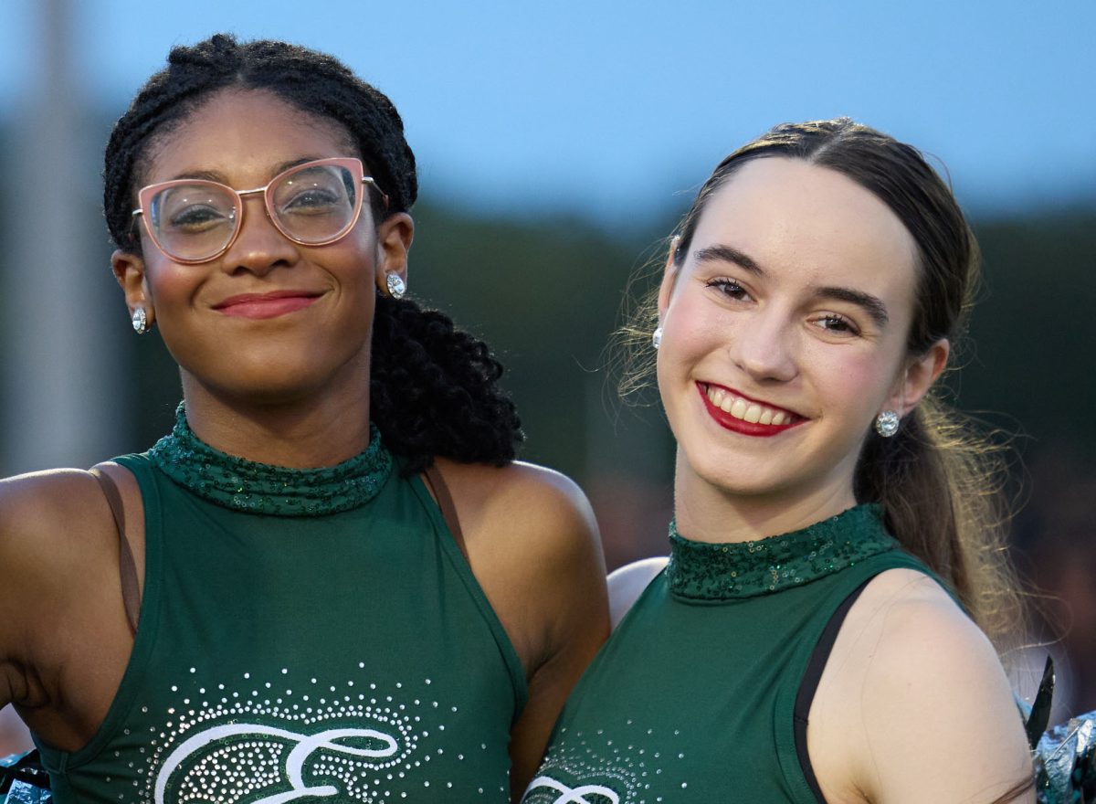 Smiling for the camera, junior Emilie Sander and senior Lily Pratt pose at Meet the Timberwolves, an annual event featuring the team. This is the first year that the Emeralds have been reinstated, after a five year absence with no JV dance team, and Sander is...
