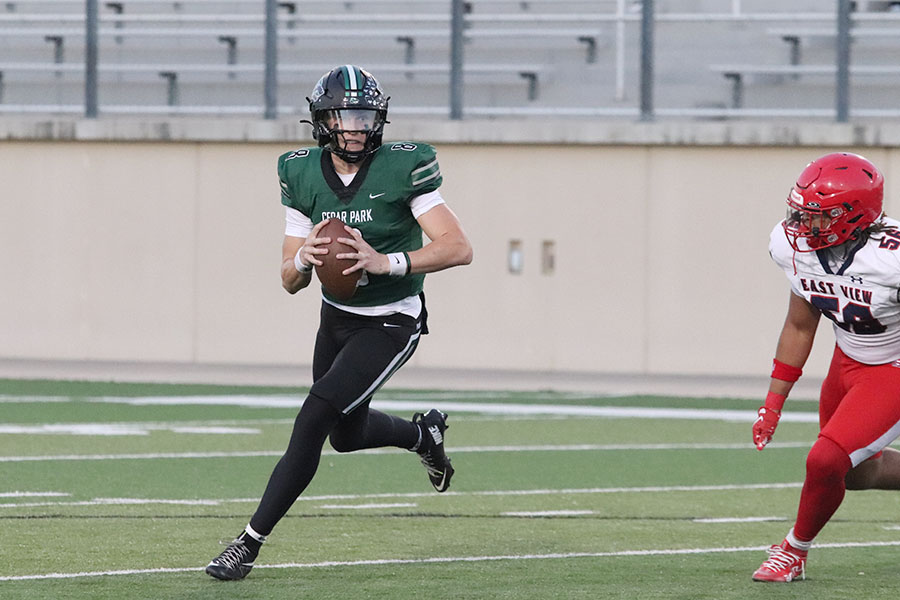 Running with the ball, junior quarterback David Cooper attempts to escape the opposing pass rush during the homecoming loss against East View. The defeat was the first loss in the homecoming game for the Timberwolves in 20 years. “We just made too many mistakes,” head football coach Michael Quintero, or Coach Q, said. “There were too many missed opportunities that we didn’t capitalize on and they did, so that’s the outcome.”