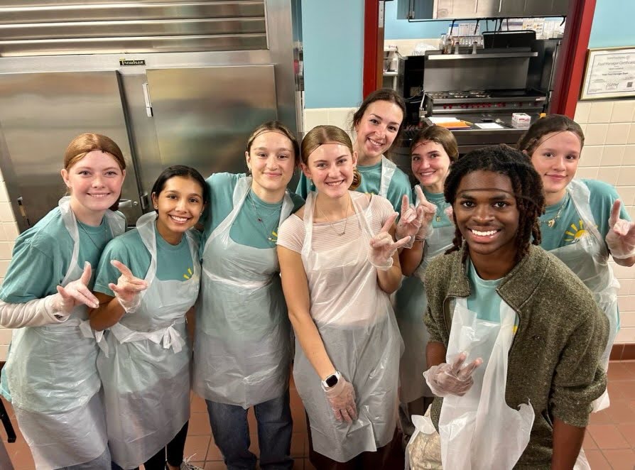 Standing in the kitchen in cooking wear, the PALS volunteer at Cypress Elementary School, serving food at the Thanksgiving family lunch. Each year. Cypress hosts a Thanksgiving Family Lunch for students to eat with their family and friends. “We get to talk about and work with people from all different walks and stages of life,” PALS Teacher Jared Lippe said. “So that’s a joy and a challenge. The preparation is just talking about the special needs of each age group and things we need to talk about and address.” Photo courtesy of PALS Instagram