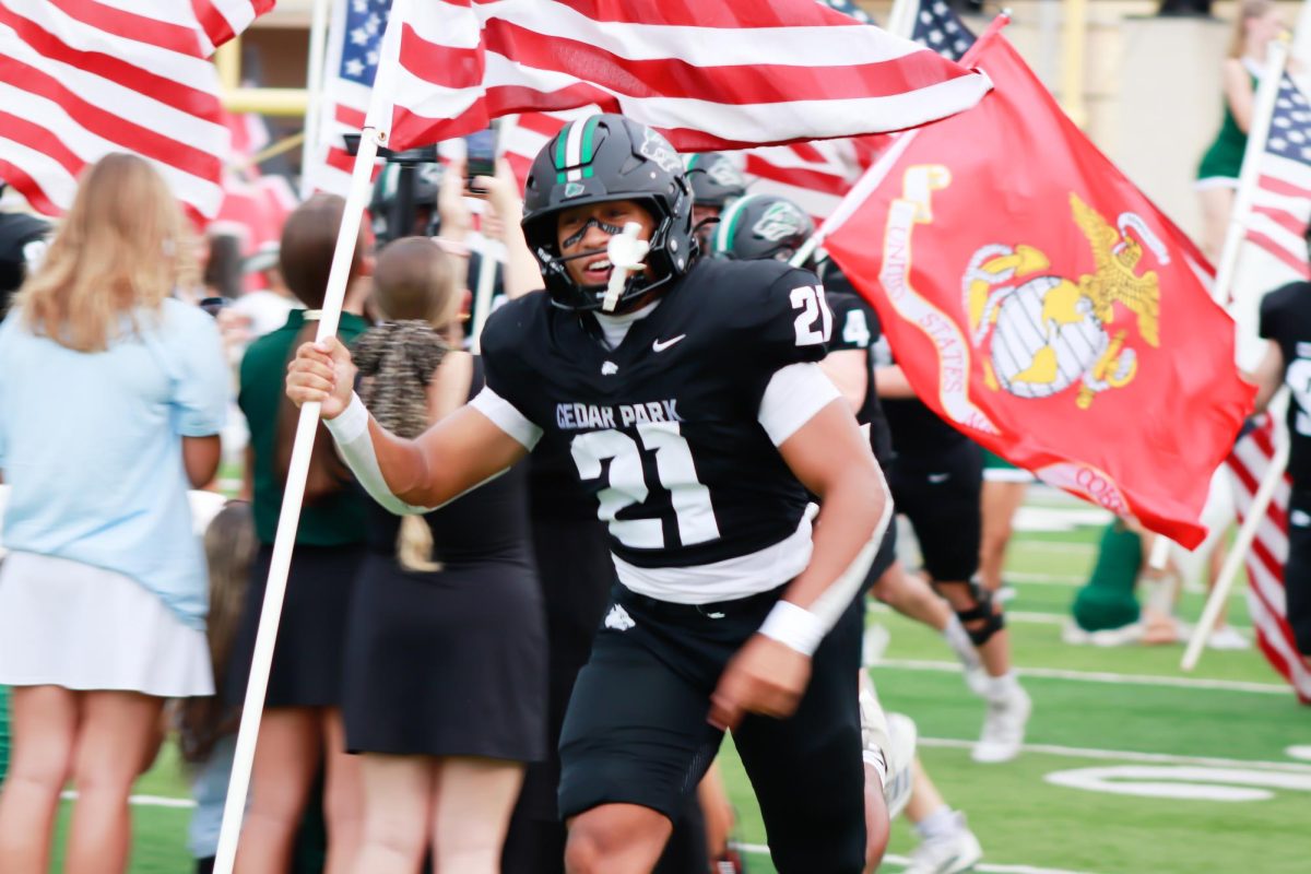 Holding an American flag, senior running back Trae Hill runs through the bust-out on Aug. 29 against Harker Heights.