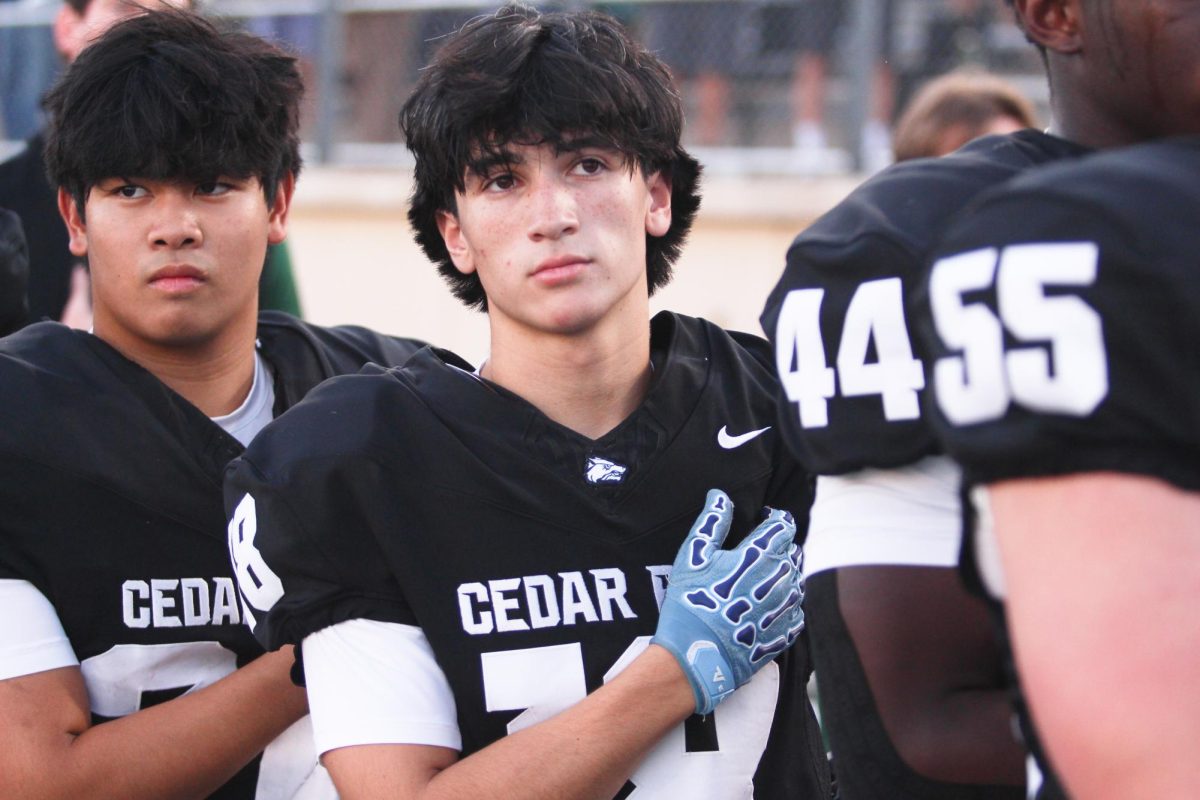 With his hand held over his heart, junior wide receiver Kysen Pham honors his country as the national anthem plays before the game against Chaparral on Sept. 25.